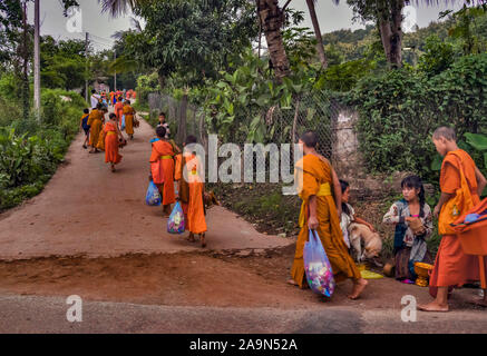 Moines en robe safran dans les rues à l'aube dans la ville classée au Patrimoine Mondial de Luang Prabang au Laos le matin l"aumône cérémonie ou Tak Bak Banque D'Images