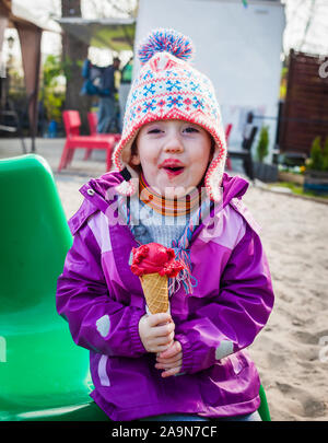 Funny little girl rend excité au sujet de manger face à la glace sur une froide journée d'hiver Banque D'Images