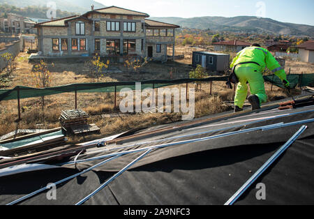 Travailleur sur le haut de la maison faire de toit. La construction d'une nouvelle maison avec toit noir. Réparer et construire la construction de toit. Pour la toiture, la conception de nouveaux h Banque D'Images