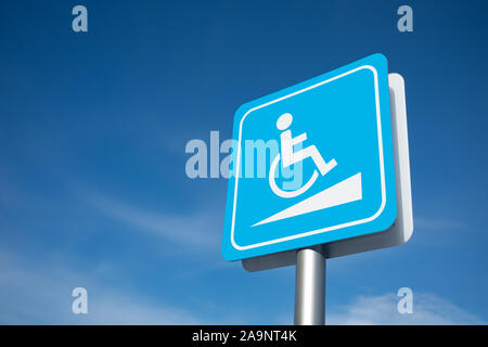 La signalisation de stationnement pour personnes handicapées sur le poteau en bleu et blanc avec fond de ciel bleu nuageux. Banque D'Images