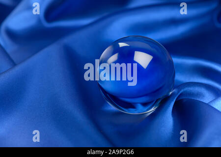 Bille de verre sur fond de soie bleue Banque D'Images