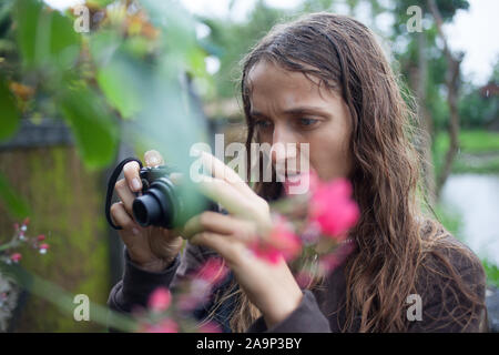 Belle jeune femme avec les cheveux ondulés dans jardin de roses Banque D'Images