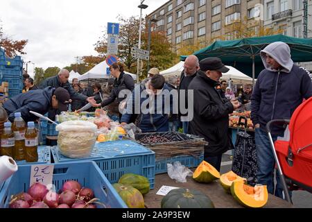 Les acheteurs de l'examen et de la sélection des fruits et légumes au marché du Midi, open air dimanche marché en dehors de la gare Bruxelles Midi Banque D'Images