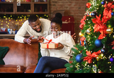 Femme noir excité déballer cadeau de Noël de son mari Banque D'Images