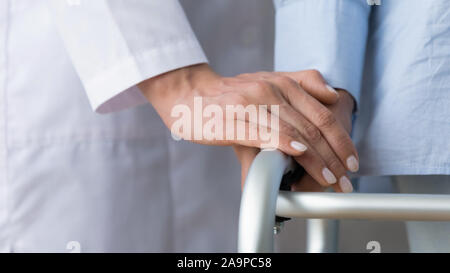 Female doctor holding senior patient la main à l'aide du cadre de marche, gros plan Banque D'Images