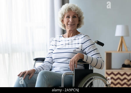 La haute mobilité heureux grand-mère s'asseoir sur le fauteuil roulant looking at camera Banque D'Images