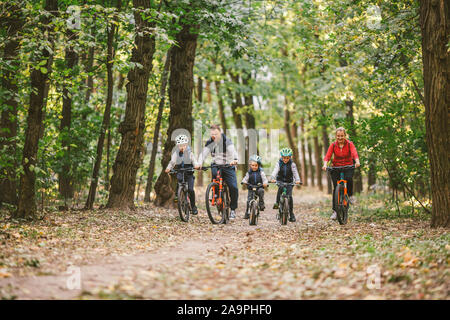 Les parents et les enfants à vélo sur piste forestière. Jeune famille à vélo dans le parc de l'automne. Famille vtt sur la forêt. Thème actif famille sports activités de plein air Banque D'Images