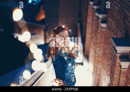 Happy young woman Playing with fairy lights à l'extérieur en ville Banque D'Images