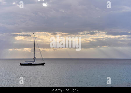 De luxe navire ancré au coucher du soleil avec des nuages et des rayons de près de Cala Saona (Formentera, Pityuses, Îles Baléares, mer Méditerranée, Espagne) Banque D'Images