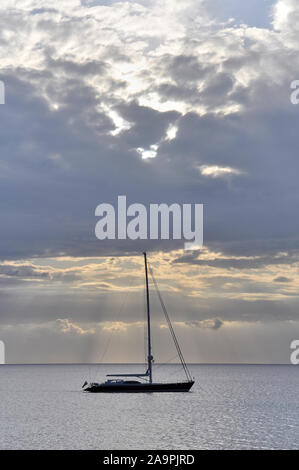 De luxe navire ancré au coucher du soleil avec des nuages et des rayons de près de Cala Saona (Formentera, Pityuses, Îles Baléares, mer Méditerranée, Espagne) Banque D'Images