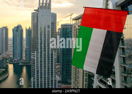 Dubaï / Emirats arabes unis - 16 novembre 2019 : Les eau vagues du pavillon sur le premier plan de la ville de Dubaï. Vue aérienne. UAE national flag. Le jour du drapeau Banque D'Images