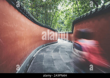 Motion blurred'promenades à travers les murs rouge passage entouré de forêt de bambou, harmonisation des couleurs appliquées, Chengdu, Chine. Banque D'Images