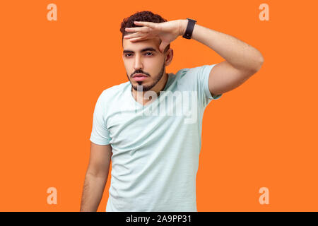 Portrait de l'homme confiant ambitieux avec barbe in Casual t-shirt blanc tenant la main au-dessus des yeux et à ce jour, la planification de la réussite dans l'avenir proche Banque D'Images