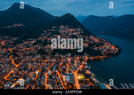 Drone aérien angle haut photo de nuit de la ville des lumières de rue par le lac Monte Brè à Lugano, Suisse Banque D'Images