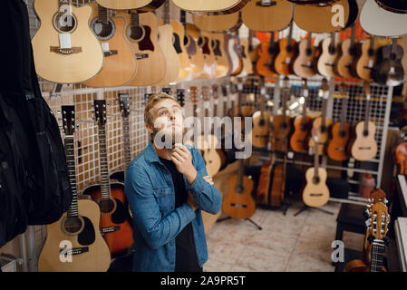 Jeune mec choix guitare acoustique dans music store Banque D'Images