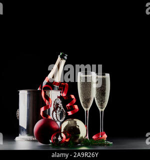 Noël et Nouvel An fête concept : deux verres de boisson gazeuse et une bouteille de champagne dans un seau à glace avec des décorations de fête Banque D'Images