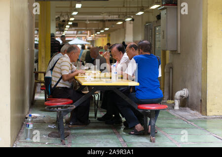 Un groupe d'hommes jouer aux dames dans un Hawker Centre à Singapour Banque D'Images