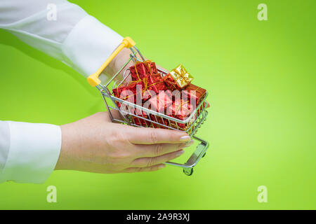 Mini panier plein de présente sur un fond vert. Concept d'achats de Noël Banque D'Images