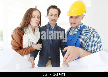 Foreman montre les plans de conception maison à un jeune couple at construction site Banque D'Images