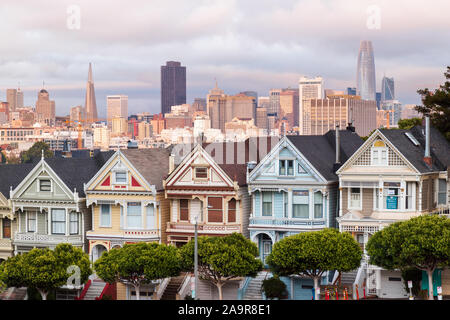 Vue sur le Painted Ladies victorian maisons en rangées avec l'horizon de San Francisco dans l'arrière-plan d'Alamo Square Park à San Francisco, Californie Banque D'Images