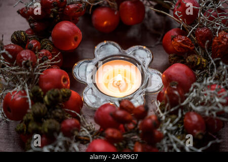 Petite couronne, avec rose hips et pommes rouges autour d'une bougie brûlante comme décor de table à l'automne, l'Avent et de Noël, temps de mise au point sélectionnée et étroit Banque D'Images