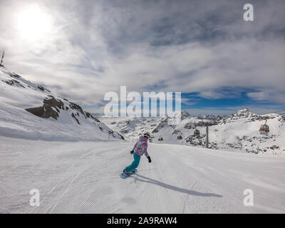 Un snowboarder en descendant la pente à Mölltaler Gletscher, en Autriche. Des pistes parfaitement entretenues. De hautes montagnes entourant la girl wearing colorful sn Banque D'Images