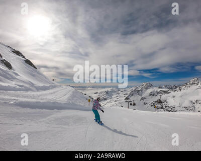 Un snowboarder en descendant la pente à Mölltaler Gletscher, en Autriche. Des pistes parfaitement entretenues. De hautes montagnes entourant la girl wearing colorful sn Banque D'Images