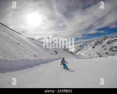 Un snowboarder en descendant la pente à Mölltaler Gletscher, en Autriche. Des pistes parfaitement entretenues. De hautes montagnes entourant la girl wearing colorful sn Banque D'Images