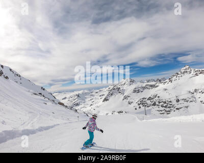 Un snowboarder en descendant la pente à Mölltaler Gletscher, en Autriche. Des pistes parfaitement entretenues. De hautes montagnes entourant la girl wearing colorful sn Banque D'Images