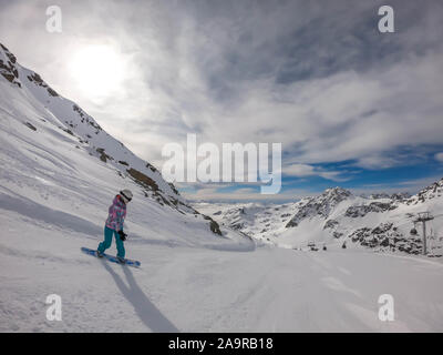 Un snowboarder en descendant la pente à Mölltaler Gletscher, en Autriche. Des pistes parfaitement entretenues. De hautes montagnes entourant la girl wearing colorful sn Banque D'Images