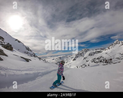 Un snowboarder en descendant la pente à Mölltaler Gletscher, en Autriche. Des pistes parfaitement entretenues. De hautes montagnes entourant la girl wearing colorful sn Banque D'Images