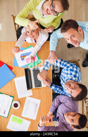Réunion de l'équipe d'affaires, les gens dans les tenues de travailler avec de statistiques financières office showing Thumbs up Banque D'Images