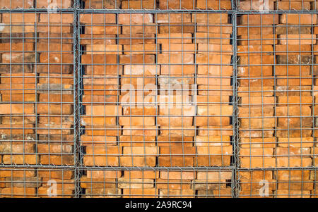 La texture de fond-vintage remis en briques rouges empilés dans une cage en métal Banque D'Images