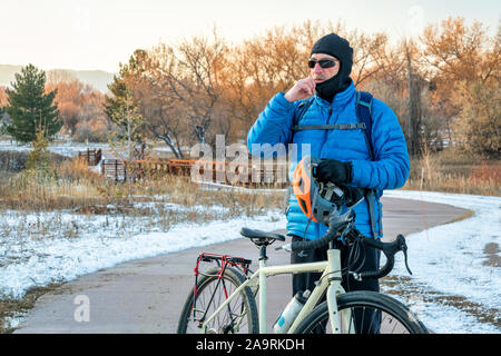 Senior male cyclist met une cagoule et un casque pour le vélo en hiver froid, ville de Fort Collins dans le nord du Colorado dispose d'un réseau dense de recr Banque D'Images