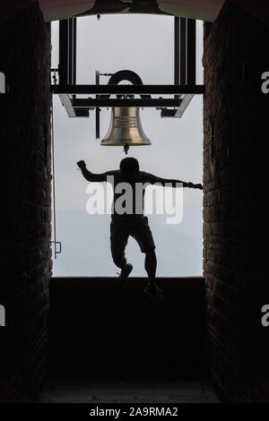 Man Jumping off Bell dans la Chapelle Santa Maria degli Angeli sur le sommet du Monte Tamaro Banque D'Images