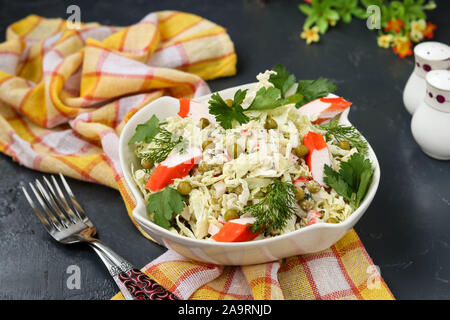 Salade saine avec le chou chinois, les conserves de petits pois et de bâtonnets de crabe dans un bol avec un arrière-plan foncé, gros plan Banque D'Images