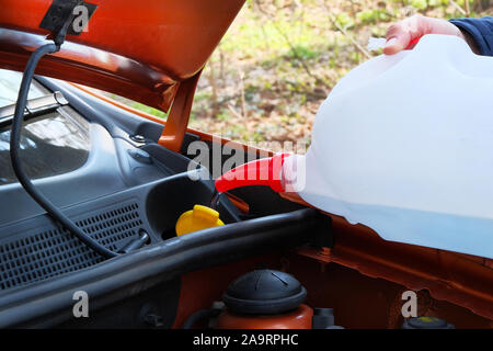 Le remplissage du liquide lave-glace en voiture. Pilote avec le liquide de lave-glace dans ses mains, Close up. Concept d'entretien des wagons. Banque D'Images