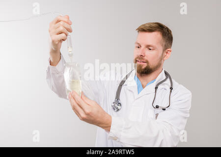 Les jeunes cliniciens-barbu avec stéthoscope holding dropper sac transparent Banque D'Images