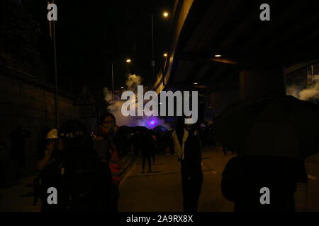 Hong Kong, Chine. 17 novembre 2019. Les manifestants, les journalistes, et de premiers soins Les bénévoles peuvent être vus fuyant les gaz lacrymogènes tirés par les policiers dans les rues de Yau Ma Tei. Répondre à un appel en ligne pour back-up par les manifestants pris au piège à l'Université Polytechnique, des manifestants tentent de pousser au-delà de la ligne de police. Quelques instants plus tôt, un homme âgé du même endroit a été emmené dans une ambulance après avoir souffert de l'effet d'être tourné à directement avec un canon à eau, ce qui l'a amené à perdre conscience et convulse violemment. Credit : Katherine Cheng/Alamy Live News Banque D'Images