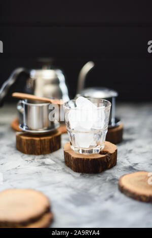 Matériel pour la préparation du café glacé style vietnamien. Verre avec des cubes de glace, col de cygne phin, électrique et de dosses sur fond sombre copy space Banque D'Images