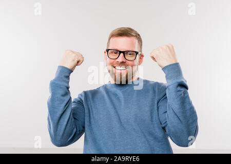 Jeune homme en bleu pull à exprimer la joie en face de l'appareil photo Banque D'Images
