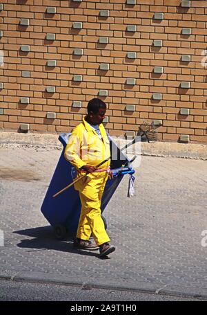 La ville de Koweït/Koweït - 10/11/2019 : rue asiatique expatrié nettoyant en salopette jaune promenades le long d'une rue dans la ville de Koweït Banque D'Images