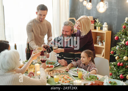 Mature et les jeunes couples toasting avec verres de vin servis sur table Banque D'Images