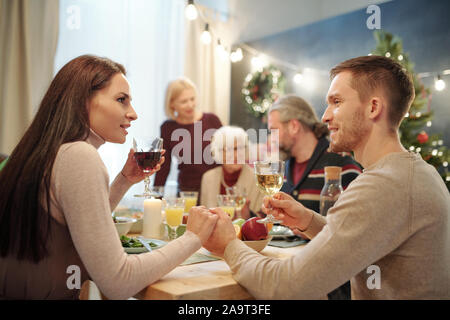 Young affectionate couple avec verres de vin de table servi par toast Banque D'Images