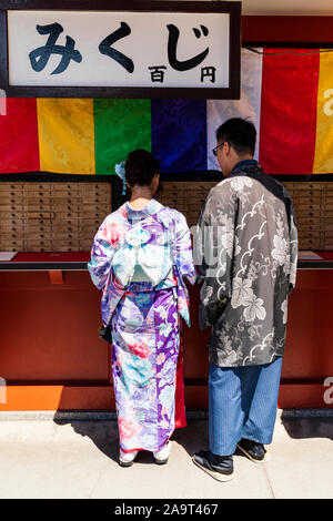 Tokyo, Asakusa shrine et temple Sensoji. Jeune couple japonais portant des costumes traditionnels en papier fortune compteur. Il porte et Haori Hakama. Banque D'Images
