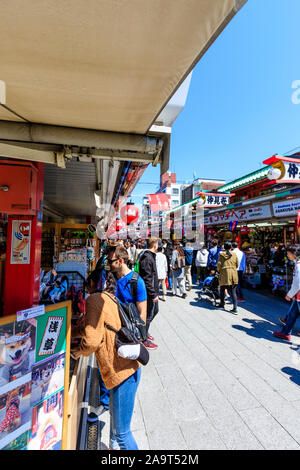 Tokyo, Asakusa shrine et temple Sensoji. La rue Commerçante Nakamise souvenir avec les gens et les touristes en passant devant l'alimentation et des boutiques de souvenirs, ciel bleu. Banque D'Images