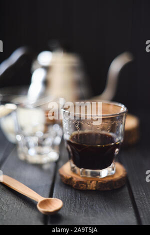 Café noir en verre sur fond noir focus sélectif avec bokeh Banque D'Images