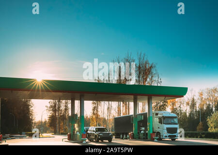 Voiture et camion-tracteur, l'unité d'entraînement, le plein à la station de gaz et de pétrole dans la région ensoleillée Journée d'automne. Banque D'Images