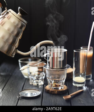 Café vietnamien faire. Verser l'eau chaude fumante en col de cygne de phin électrique sur fond noir copy space Banque D'Images