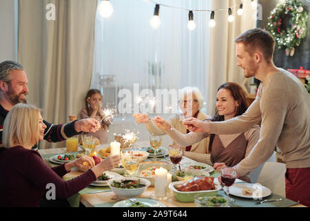 Les jeunes et les adultes de plus de feux de Bengale mousseux holding table servi Banque D'Images